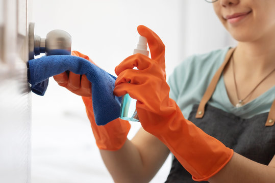 Attractive Asian Woman In Orange Rubber Gloves Wipe On Door, Doorknob With Alcohol Cleaning Spray At The House. Disinfection For Hygiene.