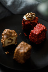 a piece of sliced cupcake in colored chocolate glaze served on a black plate a stylish composition with walnuts