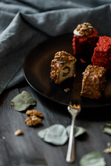 a piece of sliced cupcake in colored chocolate glaze served on a black plate a stylish composition with walnuts