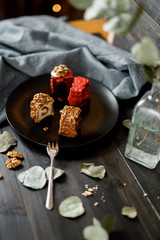 a piece of sliced cupcake in colored chocolate glaze served on a black plate a stylish composition with walnuts