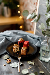 a piece of sliced cupcake in colored chocolate glaze served on a black plate a stylish composition with walnuts