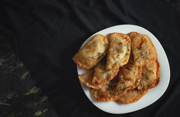 nine pork pies on a white plate on a black background
