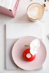 red mousse cake on a pink plate with orchid and coffee © NEZNAEV