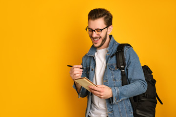 Cheerful journalist in denim casual jacket is writing something down in a notebook.