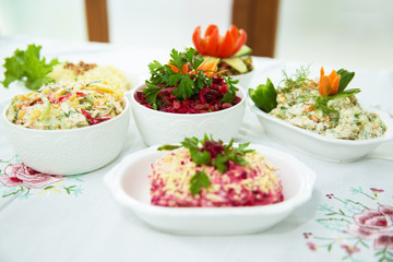 Diet salad with beets . Capital salad . Potato salad . coleslaw salad . set with different salads . Salad ham, orange pepper, mushrooms, pickles, white sauce, on a white bowl.