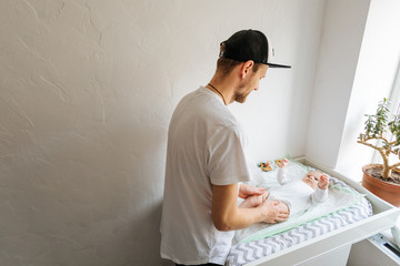 Father change diaper to baby boy on a baby changing table