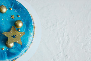 Obraz na płótnie Canvas Blue Birthday cake with colorful stars decor on the neutral background.