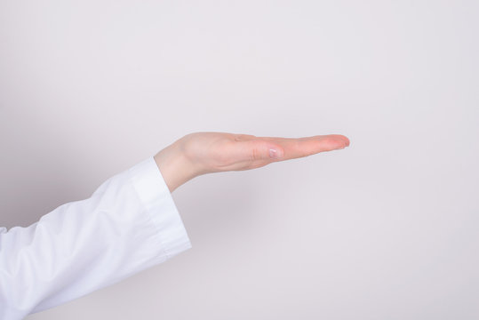 Therapy treatment remedy cure concept. Half cropped  close up photo of hand with white coat sleeve holding invisible object isolated over grey color background copyspace