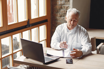 Senior with a laptop. Businessman working in the cafe. Man in a white shirt.