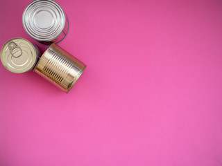 Three cans on pink background, top view with copy space