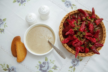 A bowl of white ceramic salt and pepper. Umac soup. Eggs beaten with salt water are sprinkled on the flour and flour is rubbed . Red Pepper in  Basket on the tablecloth Table . Bread crumbs .