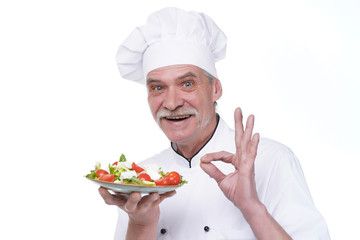 Cooking and professional culinary concept, elderly chef in white uniform holds vegetable salad stay isolated white background