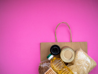 Craft package with food supplies on pink background, top view with copy space