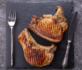 fried steaks on a stone dish with a knife and fork