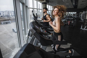 Fototapeta na wymiar Running time, photo of young sports couple making cardio workout in modern gym