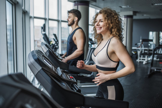 Young sports couple making cardio workout in modern gym