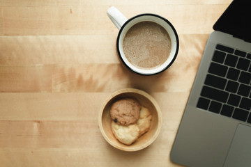 Top view of workspace with laptop and coffee cup on wooden desk.