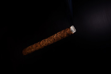 Cuban cigar lit steaming on a black background