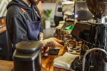 Hand of barista put a portafilter to espresso machine for brewing coffee