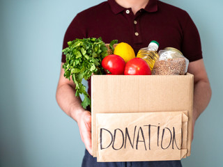 Man keeps donation box with goods in his hands, neighbourhood help concept