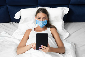 Girl In Mask Using Tablet Watching Movie Lying In Bed
