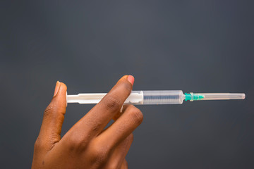 Close up of doctor's hand in medical gloves holding a syringe in front of a clinic room