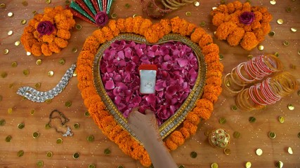 Top view shot of mehndi on woman hands preparing for Indian wedding rituals. A heart-shaped tray with bride's wedding ring surrounded by mehndi cones  bridal Chooda  sindoor  Payal and mangal sutra