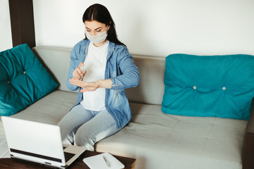 Health care and hygiene. Woman in face mask spreading sanitizer on hands before touching laptop. Infection diseases prevention. Obsessive-compulsive disorder