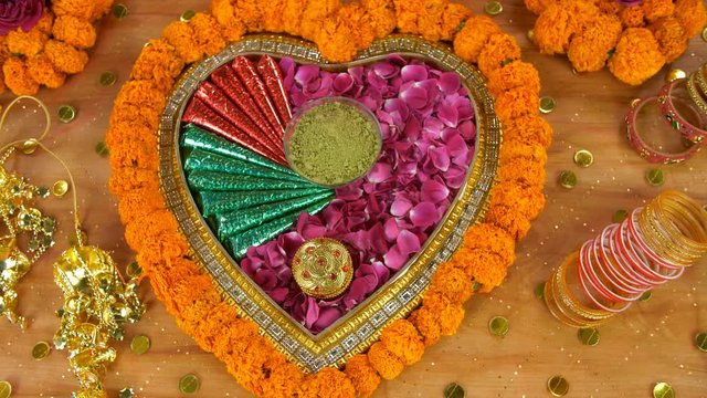 Zoom out shot of a decorated surface with wedding items - Indian wedding concept. Top view shot of beautifully decorated floral platform with sindoor box  mehndi  mehndi cones  Chooda  and Kaleerein