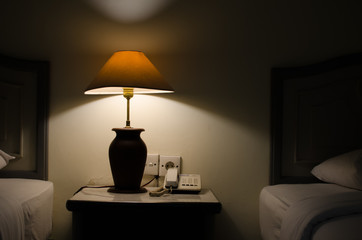 Dark bedroom with one turned on lamp