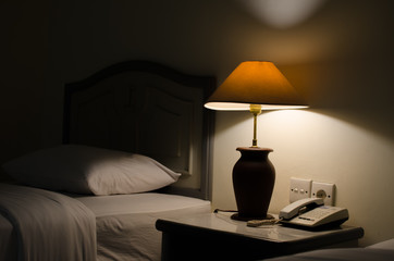 Dark bedroom with one turned on lamp