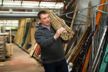 Fototapeta premium Man choosing bamboo stakes at gardening store