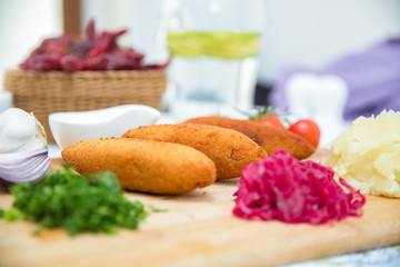 Ukrainian tradition food on a wooden board . Red cabbage sauerkraut in a small bowl . mashed potatoes . Mayonnaise, Garlic, Onion, Tomatoes. Chopped coriander.Chicken Kiev cutlets with parsley leaves.