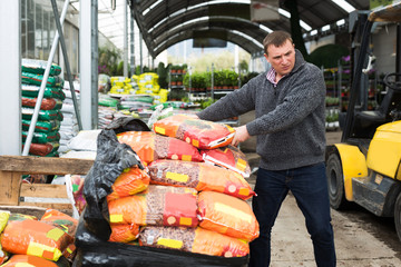 Obraz premium worker unloading garden substrates in gardening store