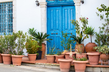 Fototapeta na wymiar beautiful old blue door with lots of ceramic pots with plants in traditional villages of Cyprus and the Mediterranean