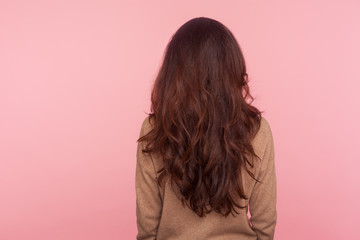 Back view of slim woman in pullover standing with thick long wavy brown hair, shampoo advertising...