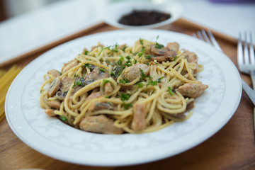 Mushrooms over spaghetti . Raw spaghetti pasta inside a bowl . Black pepper, Mayonnaise inside a bowl. Forks . Uncooked spaghetti . Delicious spaghetti wooden tray .