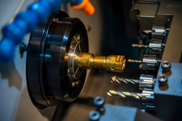 Fototapeta premium The multi-tasking CNC lathe machine swiss type tapping at the brass shaft . The hi-technology metal working process with turning machine control by CNC program