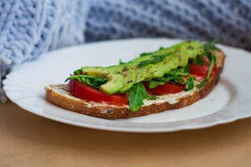 Toast of dark bread, avocado with tomato and arugula. Healthy food, breakfast of fresh vegetables.