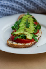 Toast of dark bread, avocado with tomato and arugula. Healthy food, breakfast of fresh vegetables.
