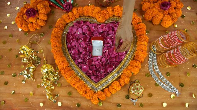 Woman hands preparing for the ceremonies performed during an Indian wedding. Top view shot of a beautiful diamond ring surrounded by mangal sutra  Payal  Chooda  sindoor  mehndi cones  and Kaleerein