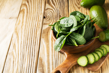 Baby spinach and avocado in wooden bowl on table, green healthy ingredient