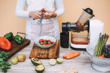Young woman preparing extracted juice with cold pressed extractor machine - Girl making smoothie...