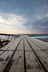 wooden bridges leading out to the sea at sunset, dark sky before a thunderstorm, a place for fishing and meditation