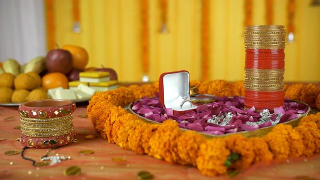 Closeup shot of wedding items placed on a decorated platform - Indian wedding / shaadi. Pan shot of beautifully decorated things worn by an Indian married woman like mangal sutra  ring  Chooda  Pay...