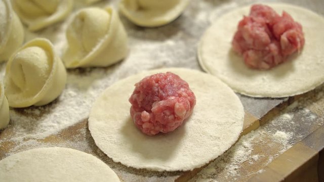 Closeup of making dumpling food. Add minced meat to a piece of dough, close up. Meat ball on a piece of dough, cooking dumplings, close-up. Pieces of dough for cooking dumplings. Sculpt dumpllings.
