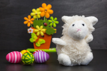 white plush toy sheep with easter eggs and flowers