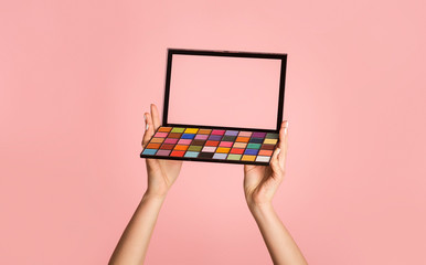 Unrecognizable woman holding eyeshadow palette on pink background, closeup. Space for design