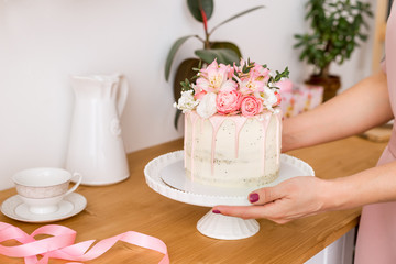 beautiful cake with flowers on a white stand in women's hands