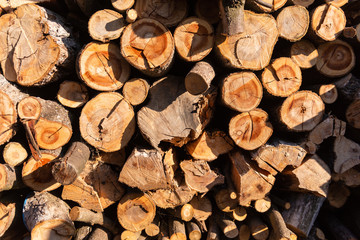 A round wood-fired wood. Wood close-up with sun and shadow. A stock of firewood in the village.